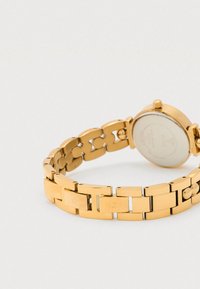 Horloge in goudkleurige tint met een armband met schakels, een gladde, glanzende afwerking, een ronde kast en een eenvoudig, strak wijzerplaatontwerp.