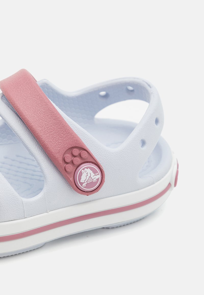 Helleblaue Sandale mit einem pinken Riemen, strukturiertem Material, Gummisohle und einem runden Logo mit einem Pferdesign auf dem Riemen.