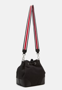 Svart hinkväska med en texturerad tygkropp och botten i konstläder. Har en dragsko för stängning och en randig axelrem i röd, vit och svart.