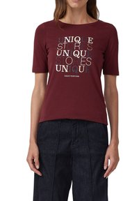 Kastanienbraunes T-Shirt mit kurzen Ärmeln aus Baumwolle, mit einem mehrschichtigen Textdruck "EINZIGARTIGE GESCHICHTEN" in kontrastierenden Farben. Glatte Textur, runder Halsausschnitt.