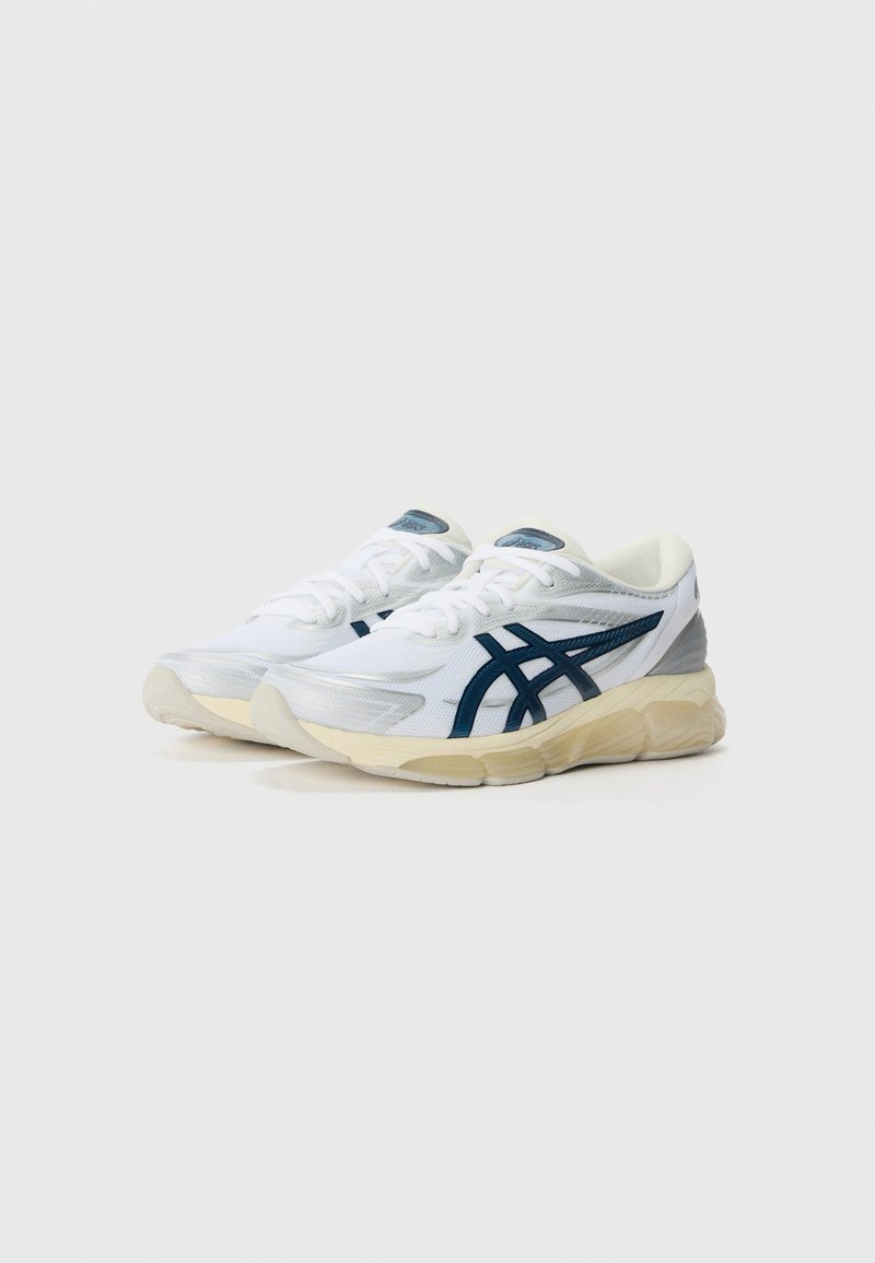 Baskets de sport blanches avec une tige en mesh respirant, des accents bleus et une semelle épaisse de couleur blanc cassé avec des motifs texturés.