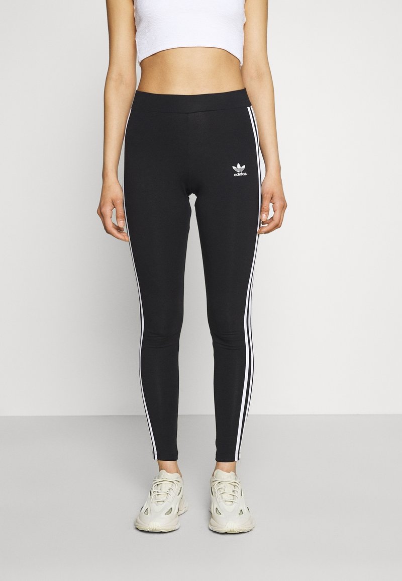 Svarta leggings med vita sidostråk och en broderad Adidas-logotyp. Tillverkade av elastiskt material med hög midja för komfort.