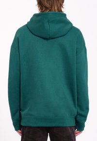 Hoodie teal avec une capuche arrondie, coupe ample, poignets et ourlet côtelés. Tissu en mélange de coton avec une texture lisse. Pas de logos ou motifs visibles.