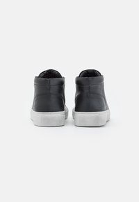 Svarta läder hög topp sneakers med en texturerad vit gummisula. Har vadderad krage och minimalistisk design.
