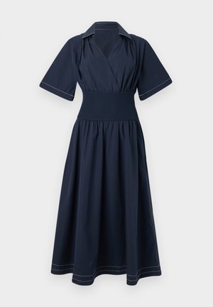 Laivansinis hihaton mekko, jossa on kuminauha vyötäröllä ja kontrastivalkoinen ompelu kauluksen ja helman ympärillä. Helppo ja ilmava hame.