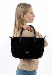 Borsa nera testurizzata con manici corti in pelle nera e un logo del marchio dorato sulla parte anteriore. Il materiale morbido e soffice conferisce un aspetto unico.