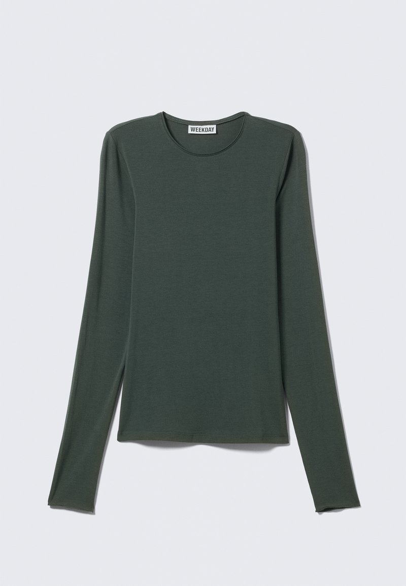 Haut à manches longues vert foncé, en tissu doux. Présente un col rond et un ourlet droit. Étiquette de la marque "WEEKDAY" visible à l'intérieur.
