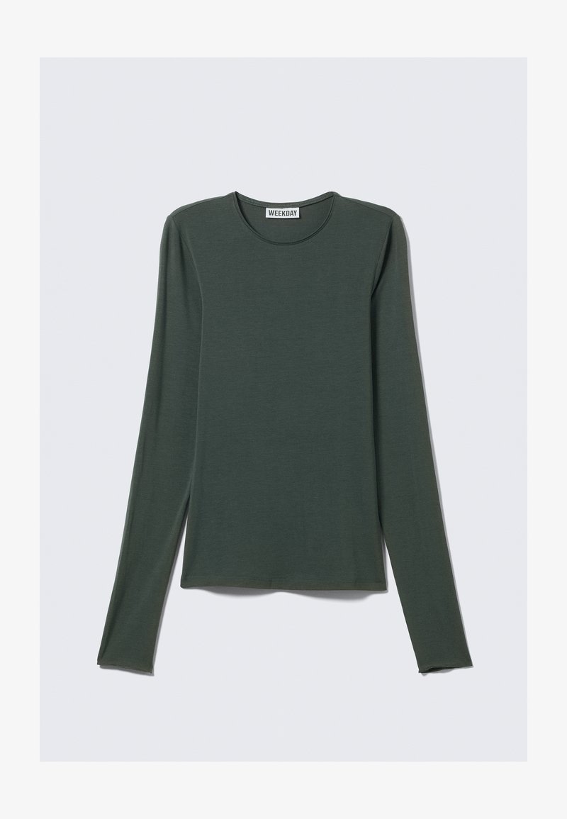 Haut à manches longues vert foncé, en tissu doux. Présente un col rond et un ourlet droit. Étiquette de la marque "WEEKDAY" visible à l'intérieur.
