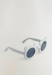 Lunettes de soleil grises avec des verres ronds et une monture en forme d'ours. Surface texturée, verres foncés et branches fines pour un design léger.