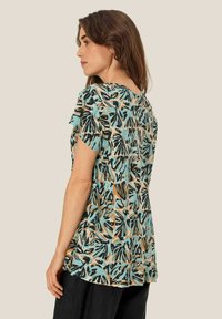 Kortärmad topp i lätt tyg, med turkos botten och svarta samt bruna bladmönster, rund halsringning och avslappnad passform.