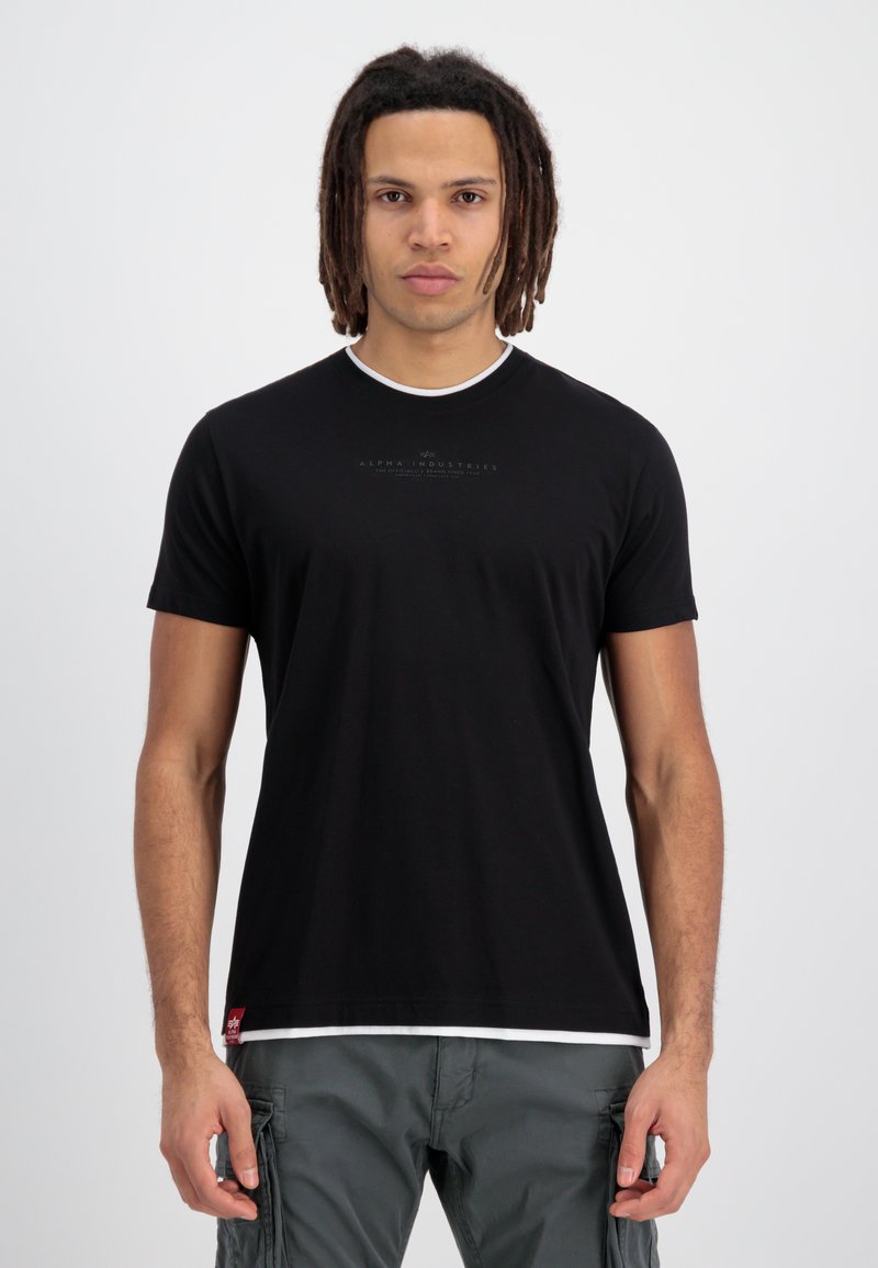 Tricou negru cu maneci scurte, cu guler rotund, cu margine albă și un logo imprimat pe față, asociat cu pantaloni cargo de culoare verde măsliniu.