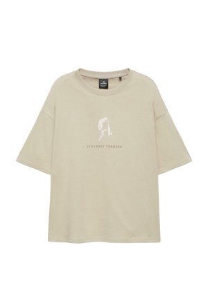 Beige oversized T-shirt med et falmet portræt af en kvinde og teksten "JOHANNES VERMEER" trykt under billedet.
