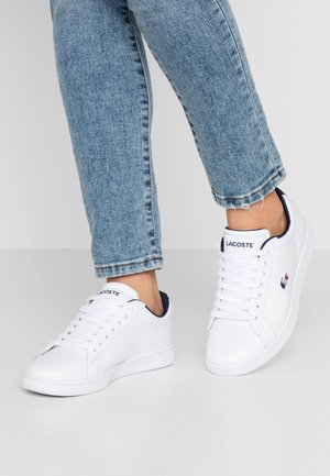 Baskets en cuir blanc avec bout arrondi, semelle en caoutchouc plate et accent bleu marine sur le col. Dotées d'une fermeture à lacets et d'un petit détail logo.