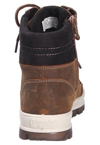 Bottine en cuir marron avec tige en suède noire, fermeture éclair et semelle texturée blanche. Présente des coutures contrastantes et un logo sur le talon.