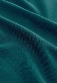 Gluos audinys giliai žalsvai mėlyna spalva, su smulkia audimo struktūra, švelniu, lygiu paviršiumi ir subtiliu blizgesiu, rodantis švelnius bangavimus ir raukšles.