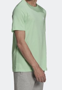 Světlezelené bavlněné tričko s krátkými rukávy, kulatým výstřihem a bílým logem na hrudi. Měkká textura, uvolněný střih.