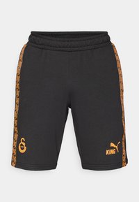 Shorts noirs en mélange de coton avec une taille élastique. Présente des accents latéraux orange avec des motifs géométriques et des logos à l'avant.