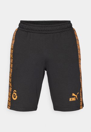 Svarte shorts laget av bomullsblanding med elastisk liv. Har oransje sideaksenter med geometriske mønstre og logoer på forsiden.