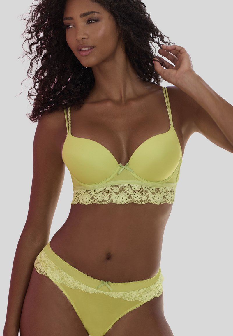 Limettengrüner BH und passender Bikini mit Spitzenrand und Schleifenakzenten. Glatte Textur mit leicht gepolsterten Cups. Verstellbare Träger für einen sicheren Sitz.
