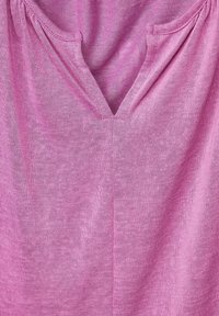 Rosa stickad topp med V-ringning och lätt sammanlagda detaljer runt halsringningen. Mjuk textur, lätt material och slät yta.