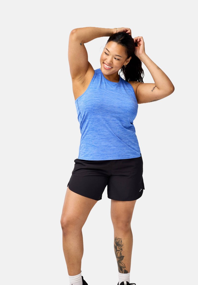 Gaiši zils sporta topiņš ar heathered tekstūru, apvienots ar melniem šortiem. Apģērbu raksturo brīvs piegriezums un sānu kabatas.