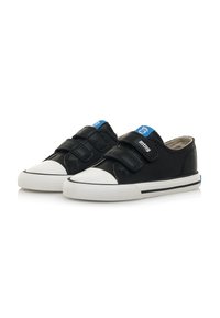 Scarpe di tela bianche e nere con design a strappo in velcro, punta tonda e una accentuazione blu sul tallone. Superficie testurizzata e suola in gomma.