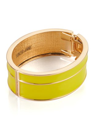 Goldfarbene Armspange mit glänzenden, neon-gelben Elementen. Sie besitzt ein glattes, breites Design und einen Scharnierverschluss. Das Innere hat eine strukturierte Goldverzierung.