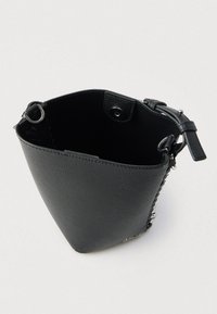 Μαύρη δερμάτινη τσάντα τύπου κουβά με υφή στην επιφάνεια, ασημένιες μεταλλικές λεπτομέρειες και ανοιχτό πάνω μέρος. Εσωτερικό με φόδρα και ευρύχωρο.