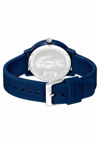 Ceas cu curea din silicon bleumarin și spate din oțel inoxidabil. Curea texturată, accesorii argintii și detaliu gravat cu logo-ul Lacoste. Rezistent la apă.