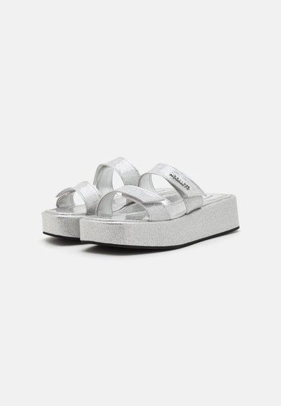 Silver plattform sandaler med glittriga remmar och tjock sula. Har två breda, korsade remmar och texturerad yta på fotsulan.