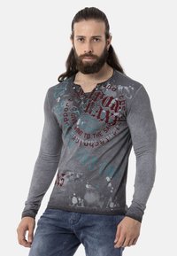 Langarm-Graues T-Shirt mit variierter Textur, ausgestattet mit grafischem Text und Mustern in Rot und Türkis. Knopfkragen und schlanke Passform.