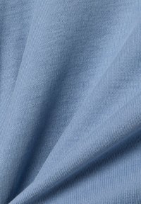 Hellblauer Baumwollstoff mit glatter Textur, der ein feines Strickmuster und einen leichten Glanz in drapierten Falten zeigt.