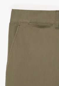 Pantalons khaki en sergé de coton épais, dotés d'un devant plat, de poches latérales et d'une surface texturée avec de subtils rayures diagonales.