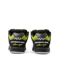 Black and neon green sneakers with textured material, padded collar, and checkered accents. Features "DC Shoe Co Sport Racing" branding.