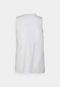 Camisa branca sem mangas com um detalhe franzido nas costas e um decote redondo, feita de um tecido leve com uma textura suave.