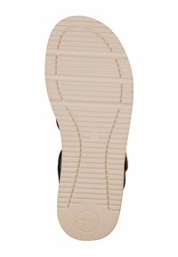 Gummisulor med ett texturerat, räfflat mönster. Off-white färg, rundade kanter och en cirkulär logotyp i bottenmitten.