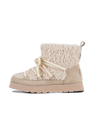 Bota de invierno beige con parte superior de shearling esponjoso, base de ante, suela gruesa y cordones de tela a rayas que se envuelven por delante y alrededor del tobillo.