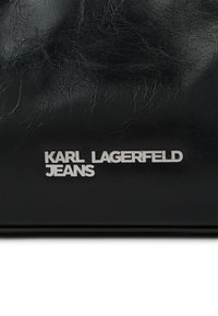 Μαύρη υφή δέρματος με το ασημί λογότυπο "KARL LAGERFELD JEANS" ανάγλυφο πάνω της.