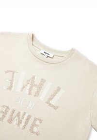 Camiseta de algodón color beige claro con cuello redondo, con detalles de cuentas texturizadas en letras que forman "SOL" y "TIEMPO."