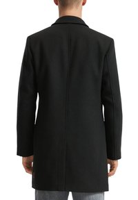 Schwarzer Wollmantel mit taillierter Silhouette, Reverskragen und Seitentaschen. Glatte Textur mit kontrastierenden Nähten.