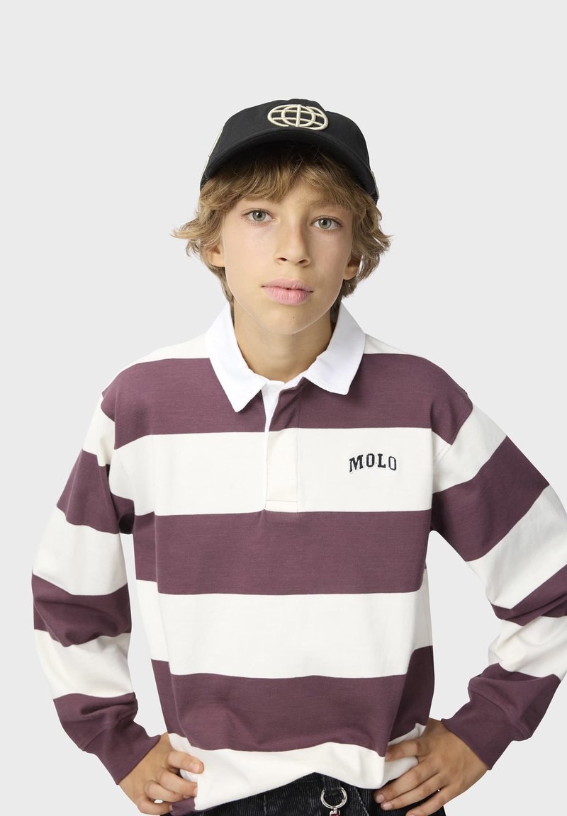 Jeune personne portant une casquette noire et un maillot de rugby à manches longues avec de larges rayures violettes et blanches et le logo « MOLO » sur la poitrine.