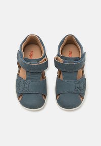 Blå lær sandaler med utskårent design og justerbar borrelåsrem, med et bjørnemotiv på remmen. Tan innermateriale og hvit såle.