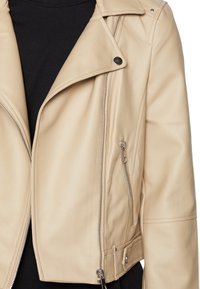 Beige motorjack van imitatieleren met een gerimpelde kraag, zilveren ritsen en zijzakken; slank model met een gladde textuur.