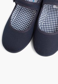 Zapatos de lona azul marino con una textura suave, puntera redondeada y forro a cuadros. El diseño incluye un borde acolchado y una correa ajustable.