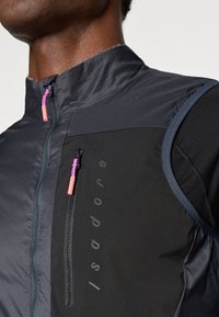 Must musta jalgrattavest kõrge kaelusega, lukuga tasku ja kontrastsete roosa ja lilla luku tõmblukkudega. Omab siledat, kerget kangast.