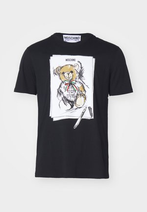 Sort bomulds T-shirt med en hvid bjørneillustration, der har en rød og grøn sløjfe, omgivet af skitseagtige detaljer og en pen grafik.