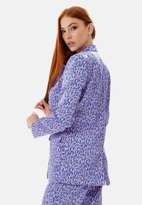 Purple patterned blazer with long sleeves, featuring a textured fabric and a distinctive abstract design in pink and blue.