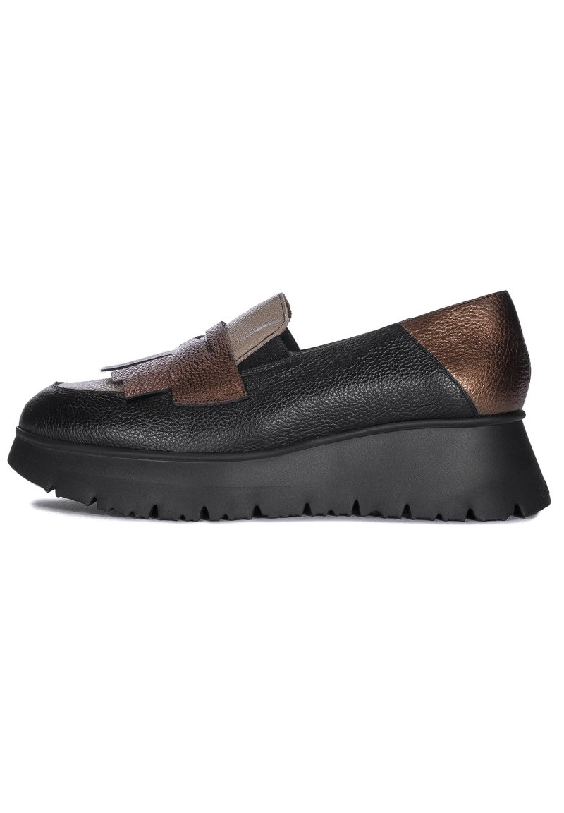 Zapato negro de cuero tipo slip-on con un cuerpo texturizado, acentos en marrón y beige, suela de plataforma con borde dentado y detalles de flecos.