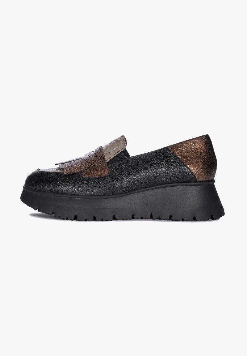 Zapato negro de cuero tipo slip-on con un cuerpo texturizado, acentos en marrón y beige, suela de plataforma con borde dentado y detalles de flecos.