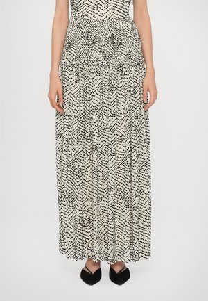 Maxi-jurk met een nauwsluitende top, zwart-wit abstract stippenpatroon, gerimpelde taille en vloeiende rok, gecombineerd met zwarte puntige ballerina's.